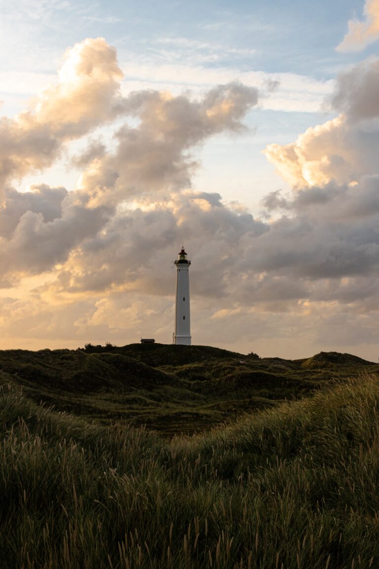 Notre site web fait peau neuve - Wide angle shot of a big white tower under a cloudy sky surrounded by grass